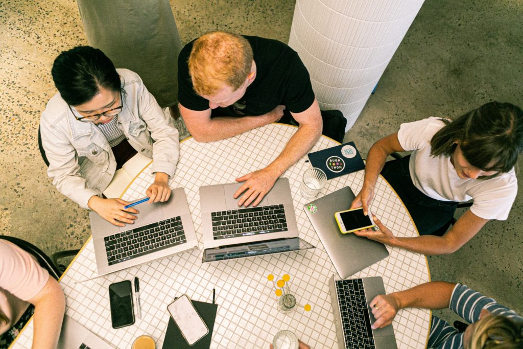 People sitting at table with laptops out.