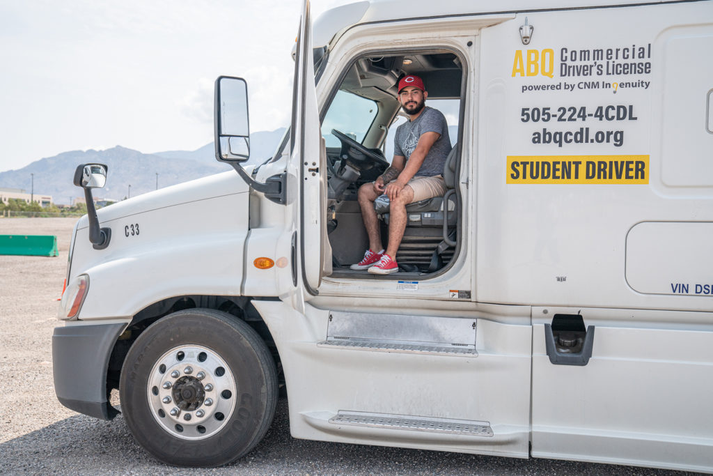 CDL student sits behind the wheel with door open, posing for picture